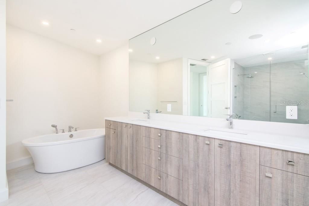 clean white bathroom at virag with a large mirror on the wall and a large white tub